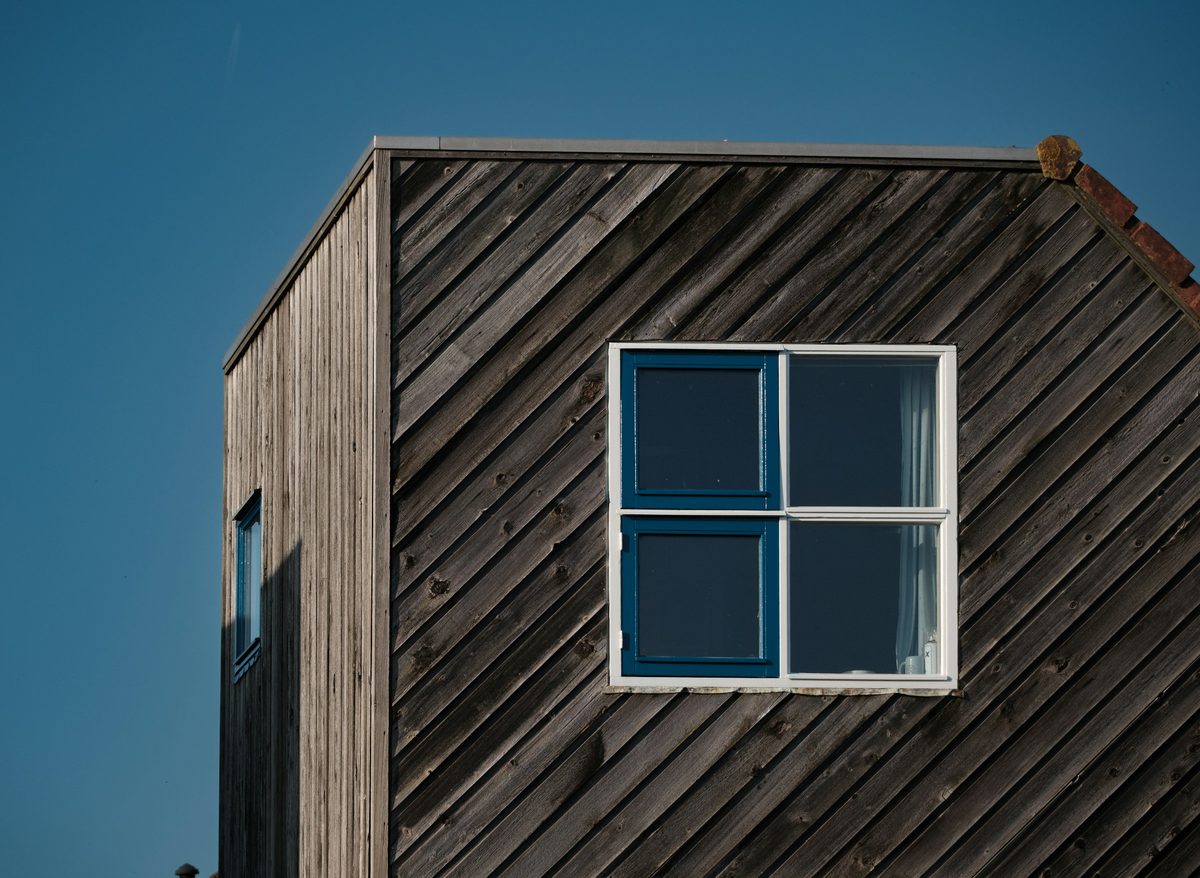 Houten woning met schuin geplaatste gevelplanken en een raam